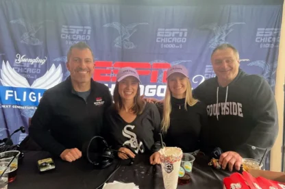 Four people stand and smile at a table with food and drinks in front of an ESPN Chicago banner. Two women wear matching light purple hats; one man wears a Southside shirt.
